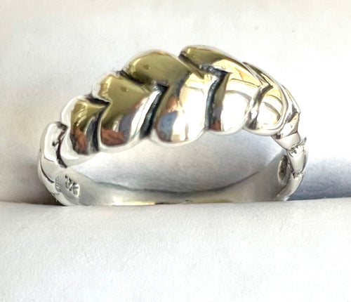 Close-up of a chunky sterling silver statement ring featuring a bold, interlocking herringbone braid design and high-polish finish.